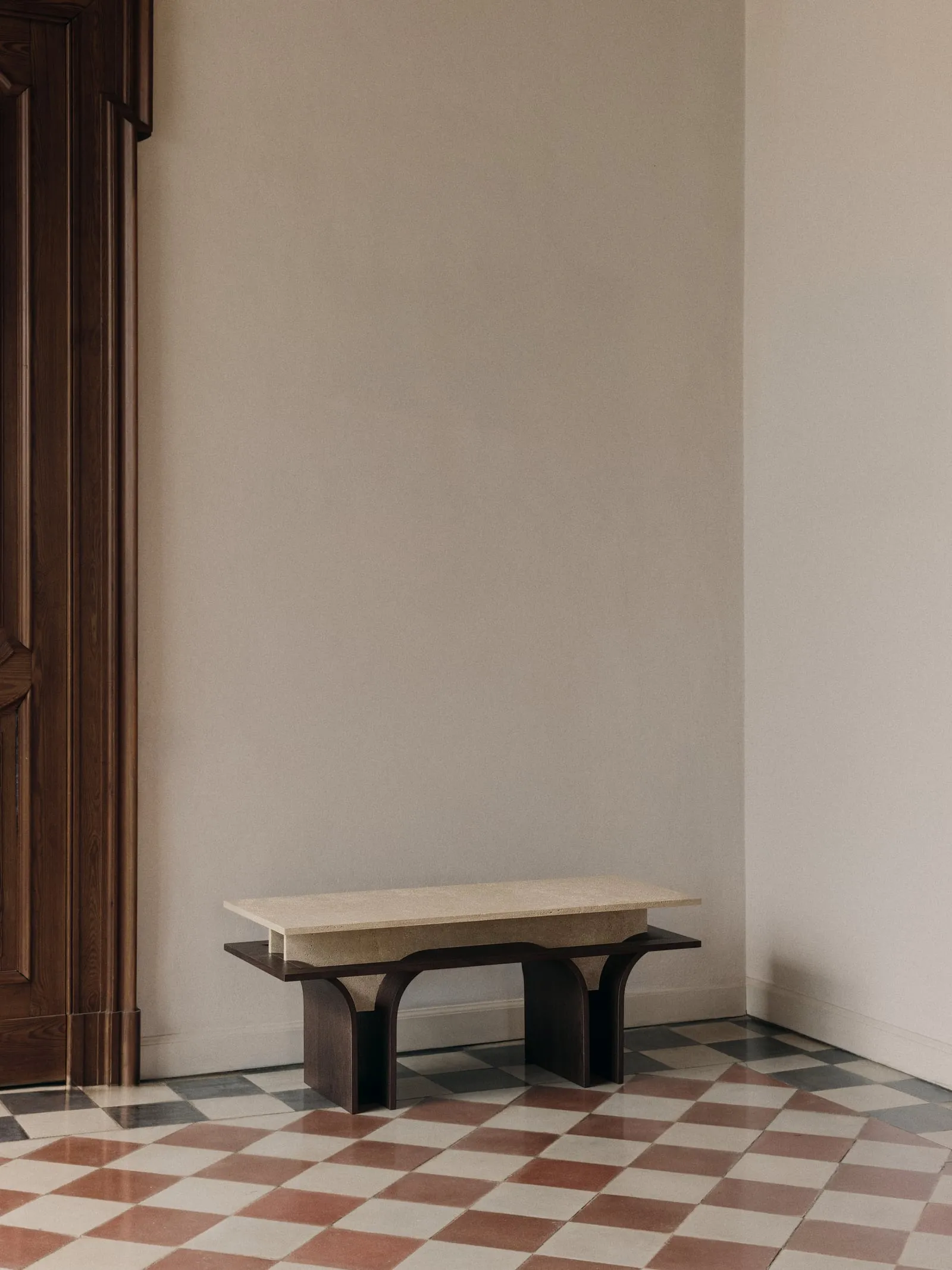 Arcus Bench from a three-quarter angle in the corner of a pale room