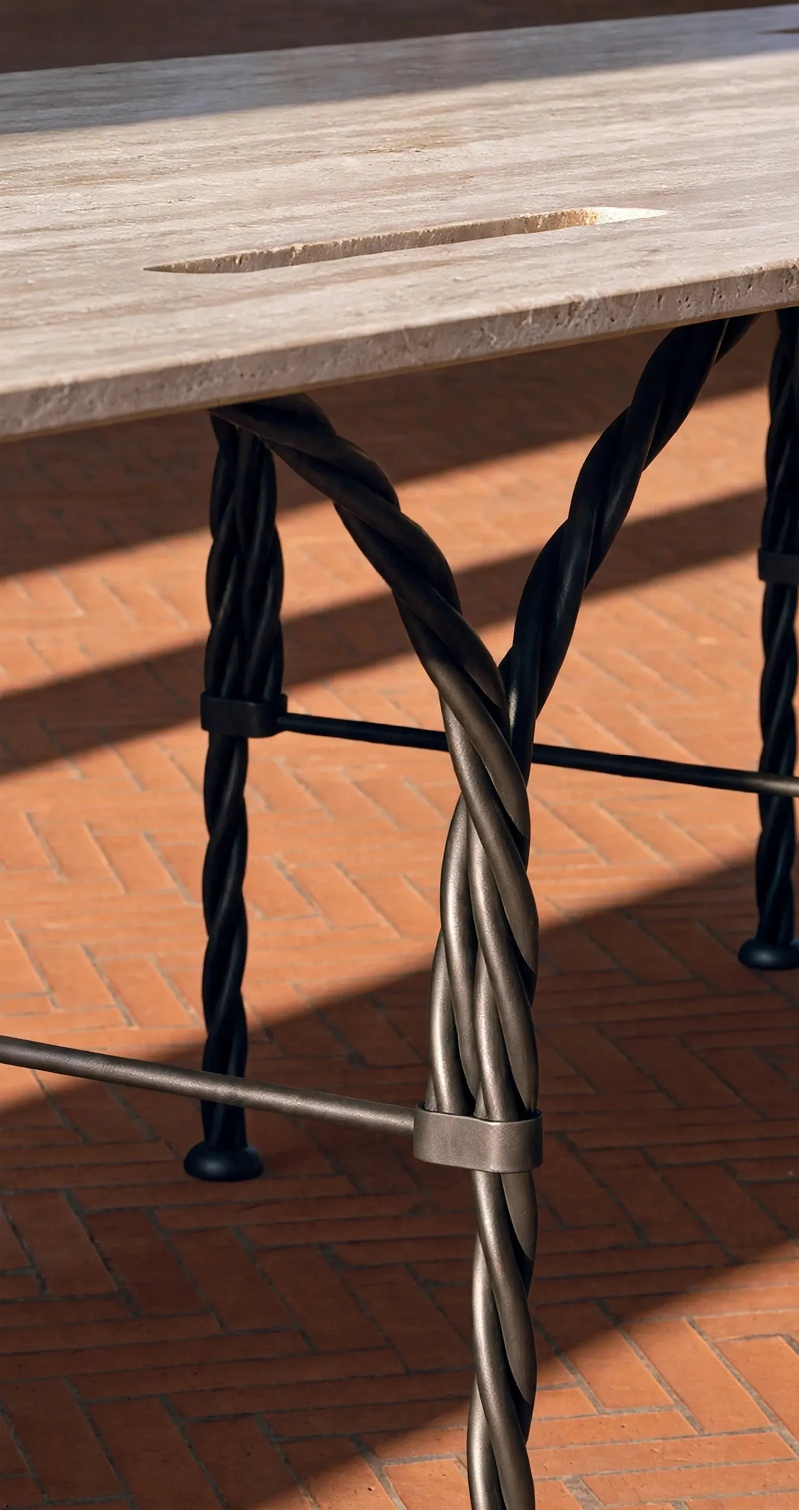 Detail of the Tresse Città Table: braided metal legs under the stone top